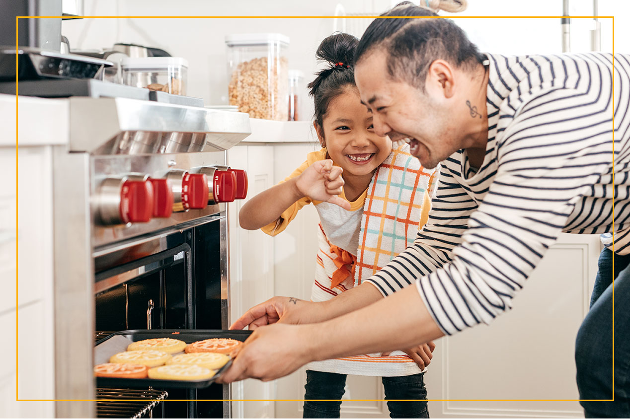 father and daughter baking cookies in oven