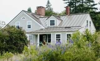 gray house with lush green garden in front under an overcast sky