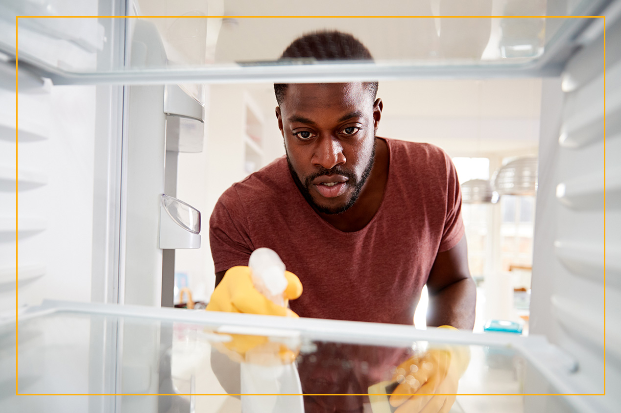 Man with spray bottle and open fridge