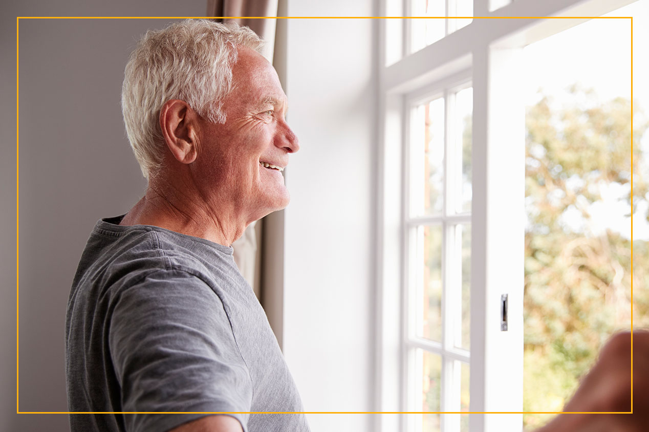 a smiling man looking out of an open window