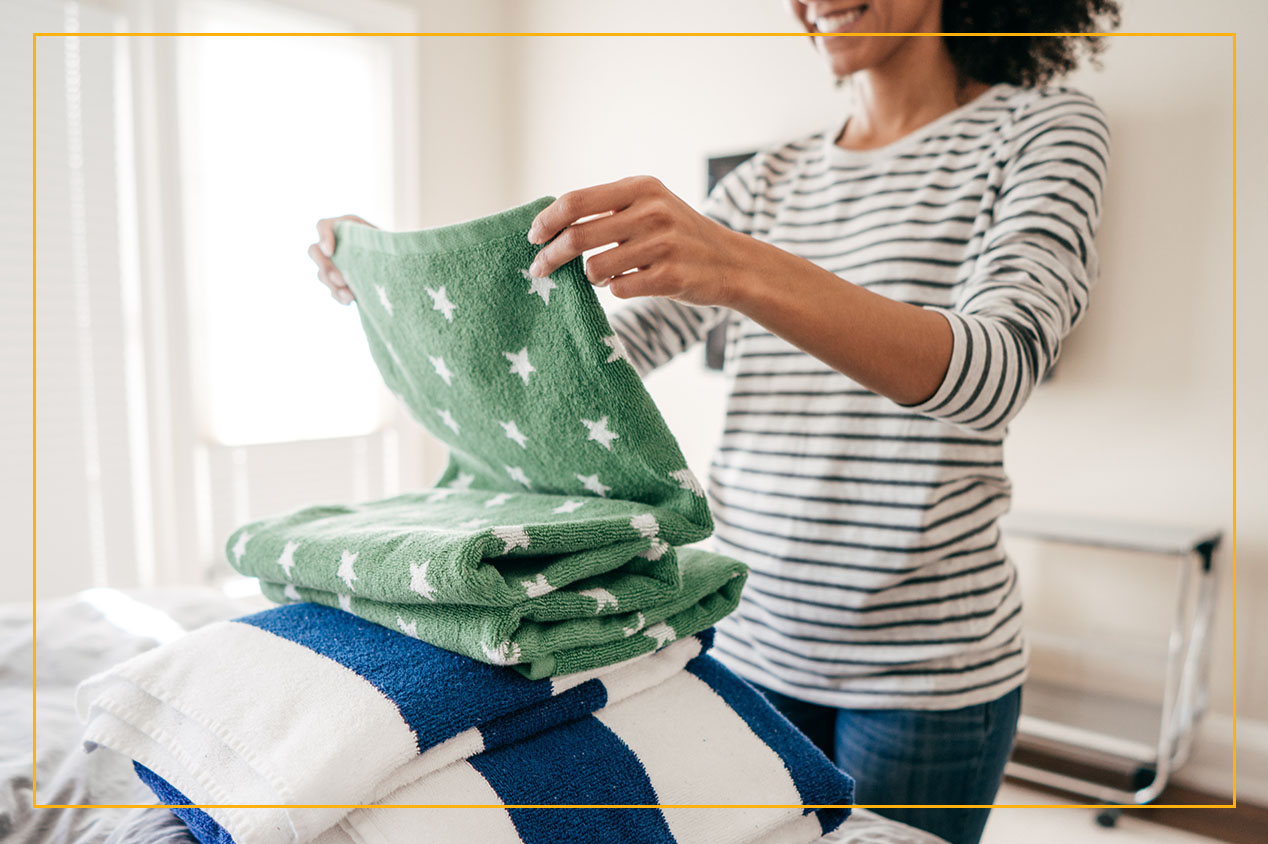 woman folding towels in bedroom