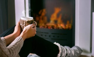 woman drinking tea near fireplace