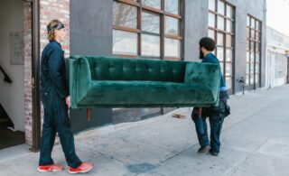 two men moving green sofa