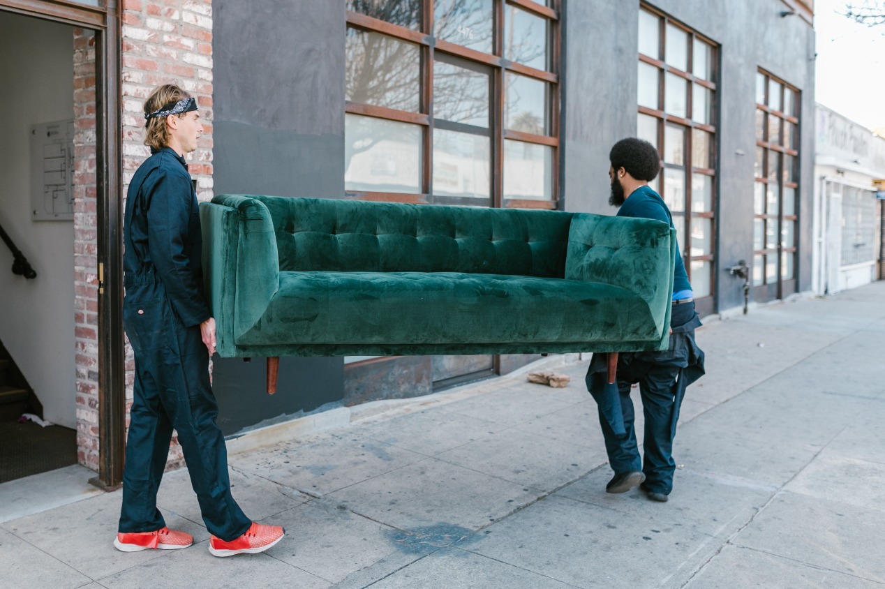 two men moving green sofa